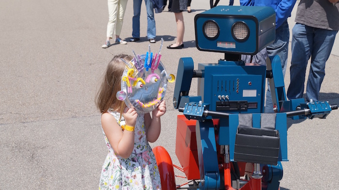 Kleines Mädchen zeigt Hugo ihre selbst gebastelte Roboter Maske