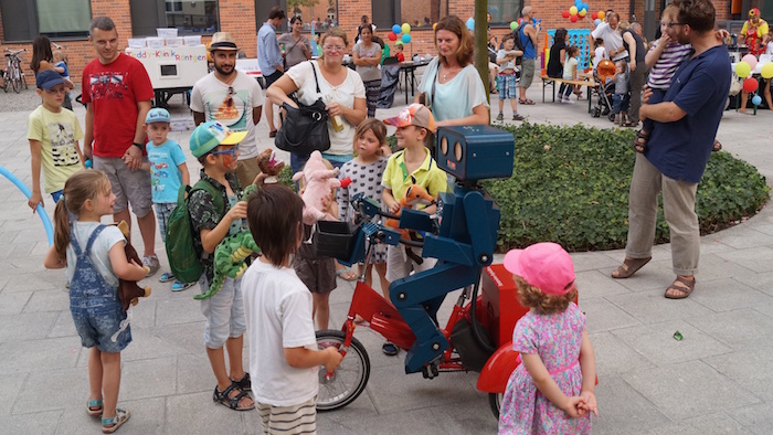 mitarbeiterfest-charite-berlin-hugo-der-sprechende-roboter-mit-fahrrad-kinder-erzaehlen-von-kuscheltieren